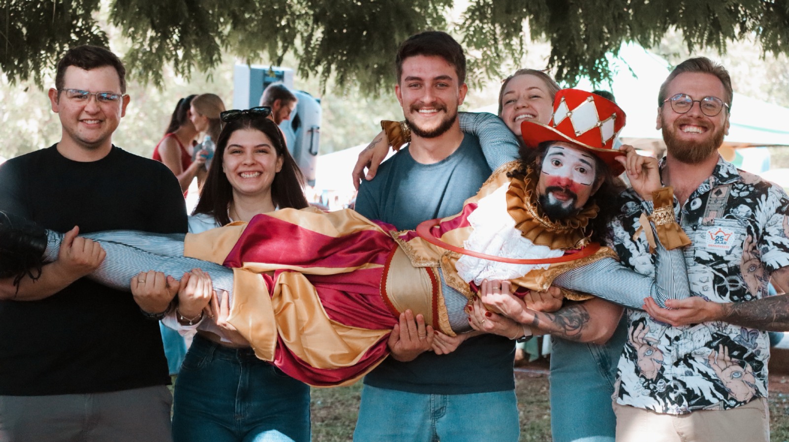 Equipe do Circo Infinito reunida ao ar livre com artista caracterizado.